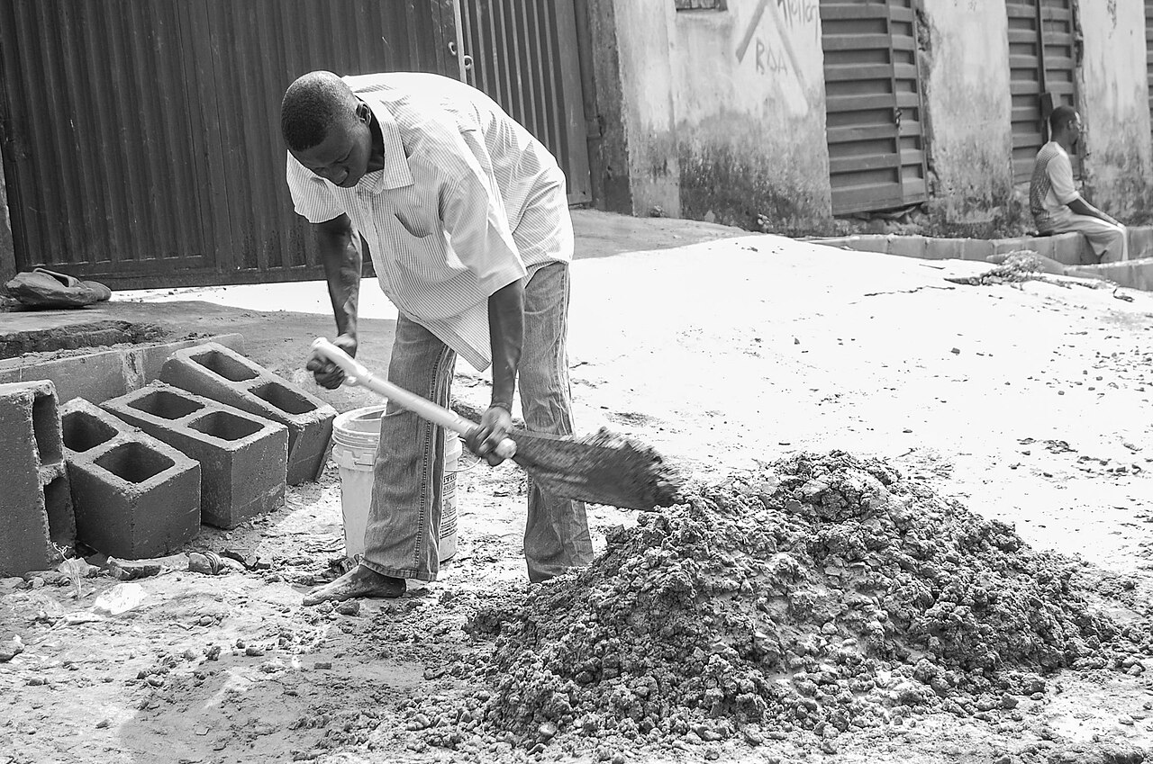 Pedreiro assentando tijolos com colher de pedreiro em parede de alvenaria